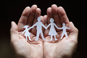 Paper cutout of a family cupped in hands