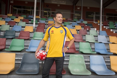 Thilo Kunkel in football jersey holding football at Griffith University sports track