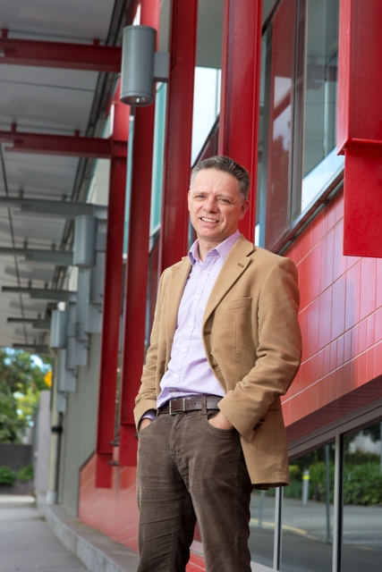 Dr Nick Barter, Griffith MBA director, three-quarter length shot, red background