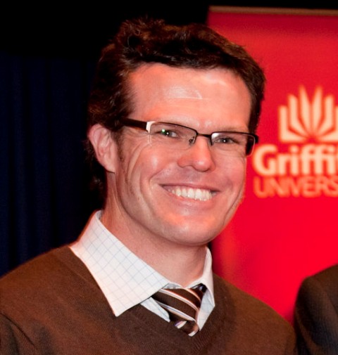 Headshot of Griffith's Brett Freudenberg, with Griffith logo partly in background.