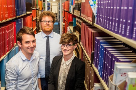 Griffith's Hult Prize team members, from left, Chris Eigeland, Brad McConachie and Elise Stephenson , in library between rows of books