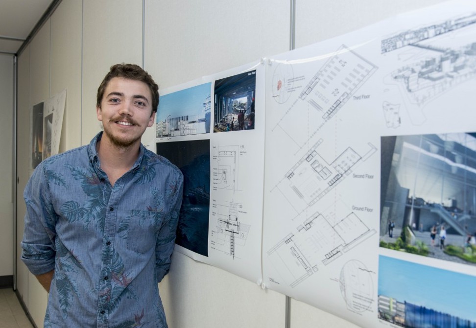 Student Matthew Bople standing in front of architecture designs
