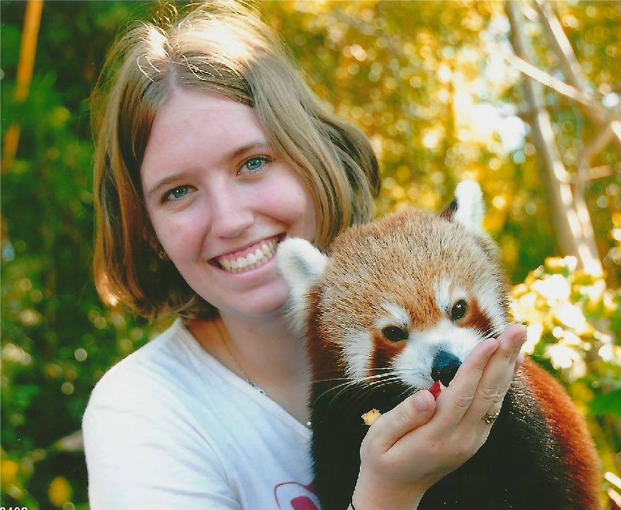 Smiling Science graduate Emma Dale, holding a red panda.