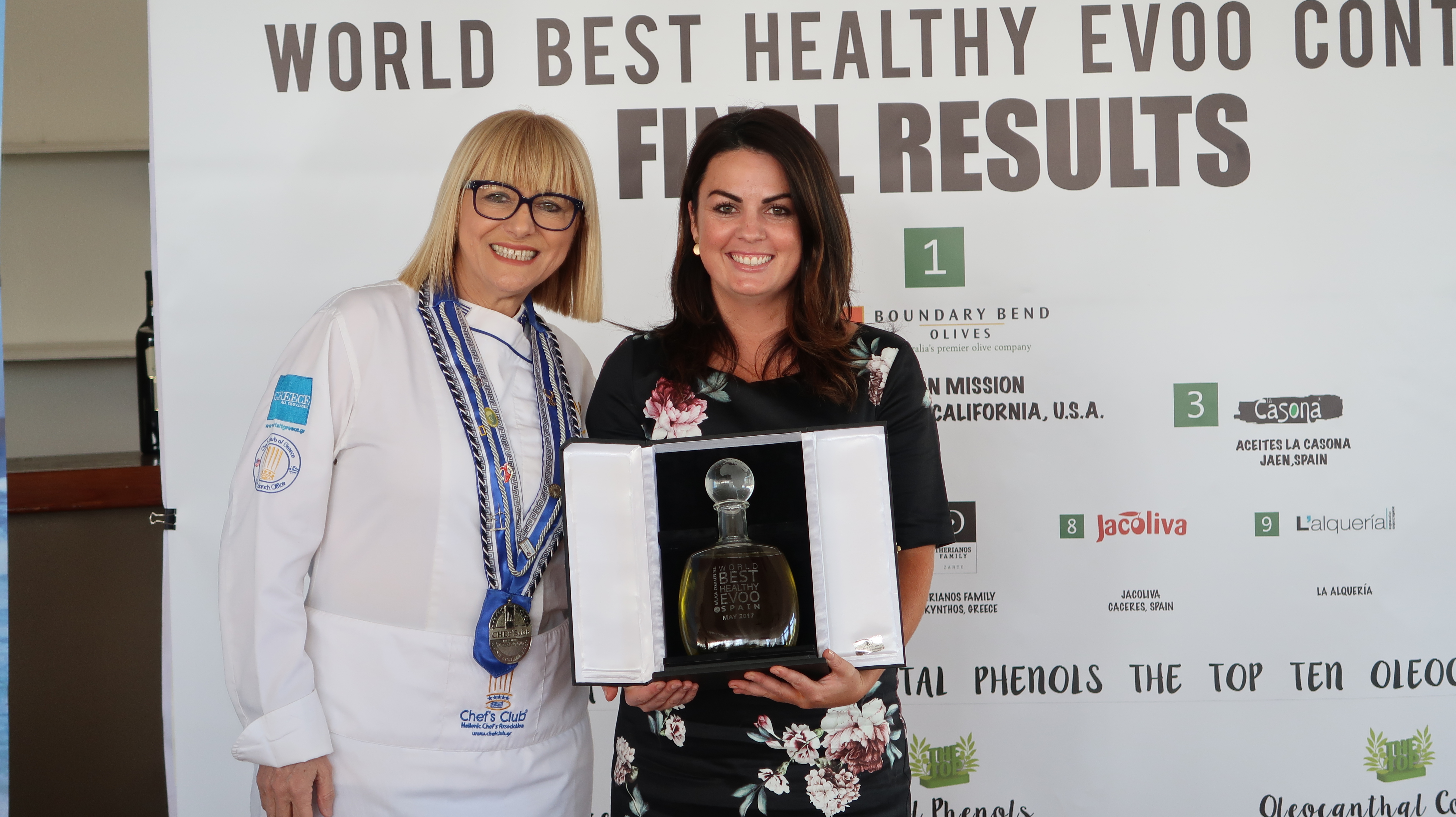 Jacqui Plozza, on stage holding plaque, accepts the Healthiest EVOO Award for Cobram Estate, presented by international chef Maria Loi