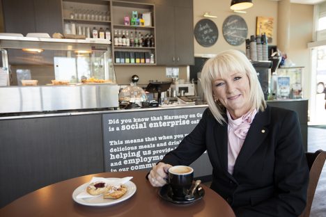 Gail Ker OAM, sitting in a coffee shop, is a force for positive impact and change in the Logan migrant community
