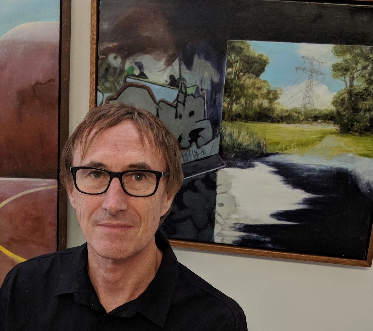 Queensland College of Art alumnus, Dennis McCart, posing in front of one of his paintings