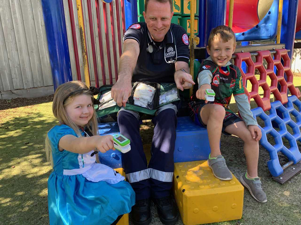 Happy Tots’ kindy kids Archer Vincent-Woodham and Addison Lippis (both 4) try out the oximeter with Griffith University paramedic lecturer Duncan’s help.