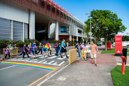 Griffith University students walking across the progress pride pedestrian crossing.