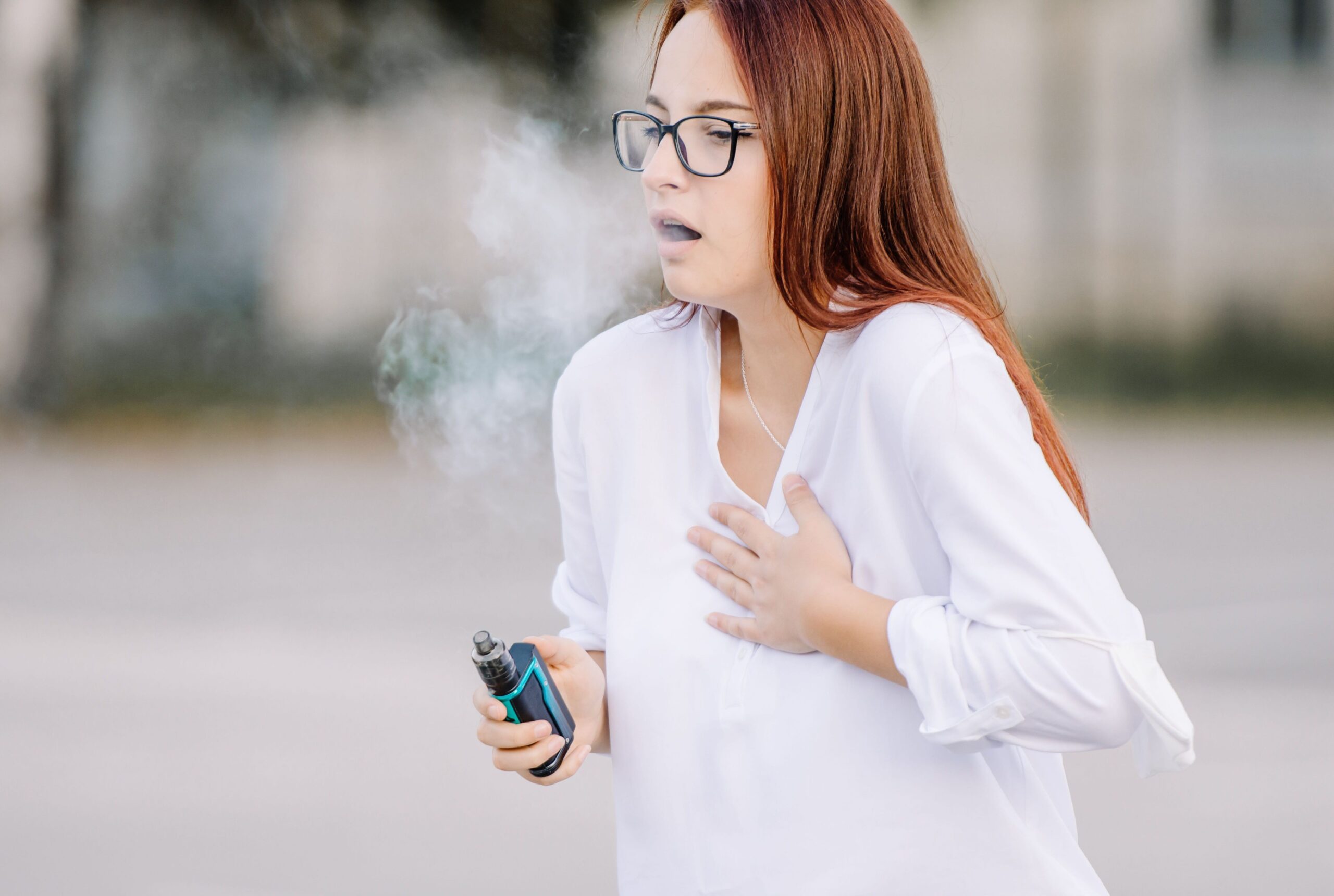 A young woman coughing after vaping