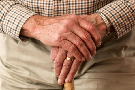 An elderly gentleman's hands, clasped over a walking stick