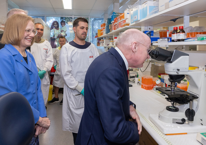 Photos of delegates touring the laboratory and looking through microscope