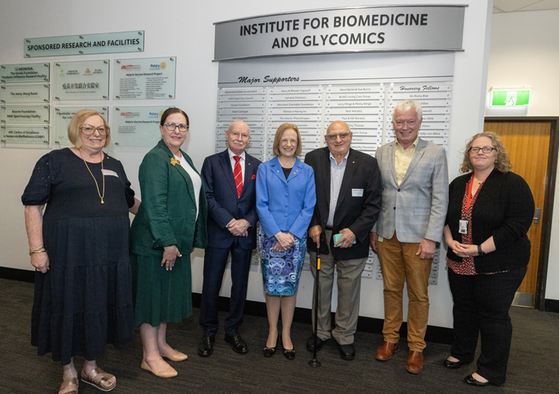 Photo of delegates in front of Institute for Biomedicine and Glycomics Major Supporters Honour Board