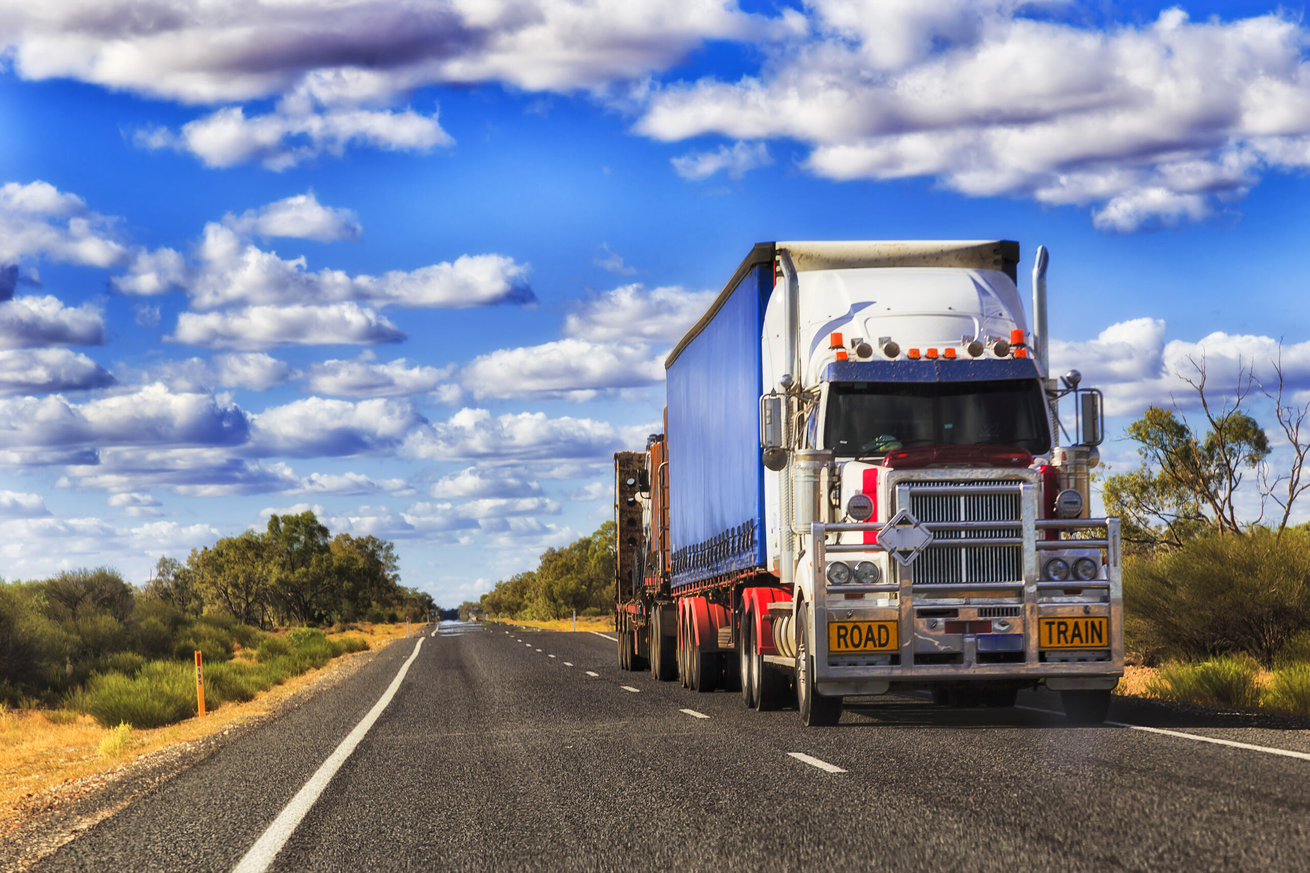 Long mighty road train truck moving cargo across Australia on a remote lonely empty outback highway.