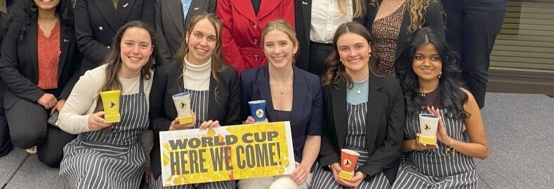 Griffith Enactus 2025 team includes 24 smiling people and a sign which reads ' World cup here we come!'.